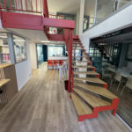 Intérieur moderne avec un escalier en bois et rouge, accueillant FORMADIA.